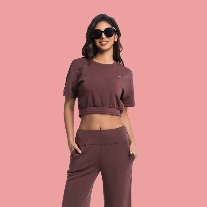 Woman wearing a brown outfit with sunglasses on a white background